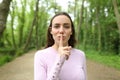 Beautiful woman asking for silence in a forest