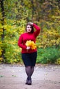 Beautiful woman in autumn, cute plus size model in red sweater outdoors, full length portrait