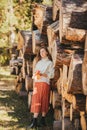 Beautiful woman with autumn maple leaves posing in the background of wood logs in forest Royalty Free Stock Photo