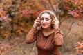 beautiful woman in an autumn park with her eyes closed listens to music through headphones Royalty Free Stock Photo