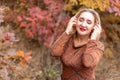 beautiful woman in an autumn park with her eyes closed listens to music through headphones Royalty Free Stock Photo