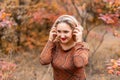 Beautiful woman in an autumn park puts on musical headphones Royalty Free Stock Photo