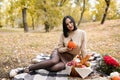 Beautiful woman on autumn picnic with flowers, fall leaves and pumpkin, thanksgiving holiday Royalty Free Stock Photo