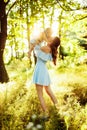 Beautiful woman with baby girl walking at the park, lovely mother kissing adorable daughter, caring parent lift in air