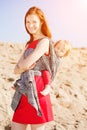Beautiful woman with a baby in a sling. Mom and baby. Mother and