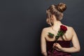 Beautiful woman back head with blonde hair updo hairdo holding red rose flower on black