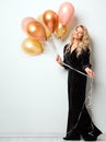 Beautiful Woman with Balloons over White background. Birthday Party Time. Fashion Model with Curly Hairstyle in Black Long Dress Royalty Free Stock Photo