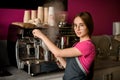 beautiful woman barista stands at coffee machine and prepares drink Royalty Free Stock Photo