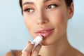 Beautiful Woman With Beauty Face Applies Balm On Lips. Skin Care