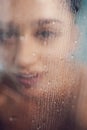 Beautiful woman behind the glass with water drops.