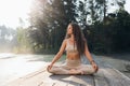 Beautiful woman in beige sportswear, practicing yoga, sitting on a mat in a lotus position, is engaged in meditation Royalty Free Stock Photo