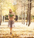 Beautiful woman being alone in the autumn park with a book