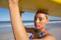 Beautiful woman in bikini carrying the surfboard on her head at beach in the sunshine Royalty Free Stock Photo