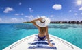 A beautiful woman in bikini with hat sits on a yacht and enjoys the summer holiday