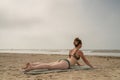 Beautiful woman in bikini sunbathing at the seaside. She is lying on a green bath towel and doing a yoga pose, looking Royalty Free Stock Photo