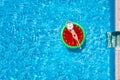 A beautiful woman in bikini takes a sunbath on a watermelon shaped float over blue pool water Royalty Free Stock Photo