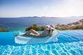 Woman enjoys the view to the Aegean Sea floating on a swimming pool, Mykonos, Greece Royalty Free Stock Photo