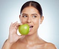 Beautiful woman biting into a green apple while posing with copypsace. Caucasian model looking contemplative while Royalty Free Stock Photo