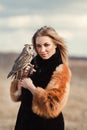 Beautiful woman in a black dress with an owl on his arm. Blonde with long hair in nature holding a owl. Romantic delicate girl Royalty Free Stock Photo