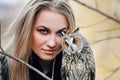 Beautiful woman in a black dress with an owl on his arm. Blonde with long hair in nature holding a owl. Romantic delicate girl Royalty Free Stock Photo