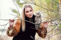 Beautiful woman in a black dress with an owl on his arm. Blonde with long hair in nature holding a owl. Romantic delicate girl Royalty Free Stock Photo