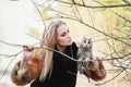 Beautiful woman in a black dress with an owl on his arm. Blonde with long hair in nature holding a owl. Romantic delicate girl