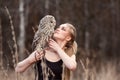 Beautiful woman in a black dress with an owl on his arm. Blonde with long hair in nature holding a owl. Romantic delicate girl Royalty Free Stock Photo