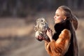 Beautiful woman in a black dress with an owl on his arm. Blonde with long hair in nature holding a owl. Romantic delicate girl Royalty Free Stock Photo