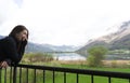 Beautiful woman in a black dress smiling at sunset on a background of mountains and a lake. Laughing girl in a balcony with cloudy Royalty Free Stock Photo