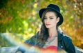 Beautiful woman with black hat posing in autumnal park. Young brunette spending time during autumn in forest Royalty Free Stock Photo