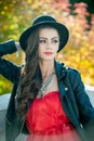 Beautiful woman with black hat posing in autumnal park. Young brunette spending time during autumn in forest Royalty Free Stock Photo