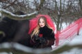 Beautiful woman with a black horse in winter. with a red rose in a red veil