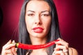 Beautiful woman in black lace lingerie posing in studio with red background. She is playing with chili pepper. Royalty Free Stock Photo