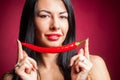 Beautiful woman in black lace lingerie posing in studio with red background. She is playing with chili pepper. Royalty Free Stock Photo