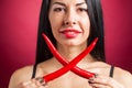 Beautiful woman in black lace lingerie posing in studio with red background. She is playing with chili pepper. Royalty Free Stock Photo