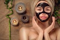 Beautiful woman with black purifying black charcoal mask on her face. Beauty model girl with black facial peel-off mask Royalty Free Stock Photo