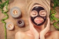 Beautiful woman with black purifying black mask on her face. Beauty model girl with black facial peel-off mask lying in spa salon Royalty Free Stock Photo