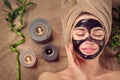 Beautiful woman with black purifying black charcoal mask on her face. Beauty model girl with black facial peel-off mask Royalty Free Stock Photo