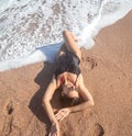 Beautiful woman in a bathing suit lying on the sand by the sea top view Royalty Free Stock Photo