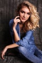 Beautiful woman with blond curly hair and evening makeup,wears jeans clothes Royalty Free Stock Photo