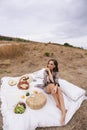 Beautiful woman with blond hair in elegant dress having picnic with mountains view Royalty Free Stock Photo