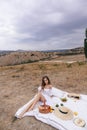 Beautiful woman with blond hair in elegant dress having picnic with mountains view Royalty Free Stock Photo