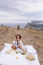 Beautiful woman with blond hair in elegant dress having picnic with mountains view Royalty Free Stock Photo