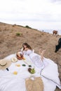 Beautiful woman with blond hair in elegant dress having picnic with mountains view Royalty Free Stock Photo