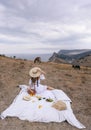 Beautiful woman with blond hair in elegant dress having picnic with mountains view Royalty Free Stock Photo