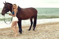 Beautiful woman with blond hair posing with black horse Royalty Free Stock Photo