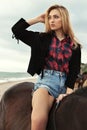 Beautiful woman with blond hair posing with black horse Royalty Free Stock Photo