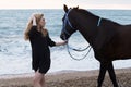 Beautiful woman with blond hair posing with black horse Royalty Free Stock Photo