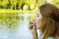 Beautiful woman blowing bubbles in the summe near the lake Royalty Free Stock Photo