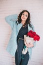 Beautiful woman in blue coat with red roses in craft paper